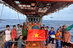 Las fuerzas de seguridad marítima de Ciudad Ho Chi Minh presentan la bandera nacional para los pescadores en alta mar. Foto: VNA