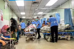 Un auxiliar médico (vestido con pantalones y zapatos negros) traslada a un paciente en una camilla por el pasillo, una zona pública, del departamento de urgencias y traumatología del Hospital Raja Permaisuri Bainun, en Ipoh, Perak (Fuente: codeblue.galencentre.org)