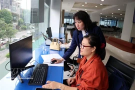 Funcionarios del Centro de Servicios Administrativos Públicos de la Ciudad de Hanoi gestionan trámites administrativos para los ciudadanos. (Foto: VNA)