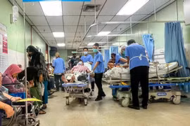 Un auxiliar médico (vestido con pantalones y zapatos negros) traslada a un paciente en una camilla por el pasillo, una zona pública, del departamento de urgencias y traumatología del Hospital Raja Permaisuri Bainun, en Ipoh, Perak (Fuente: codeblue.galencentre.org)