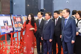 Tran Cam Tu, miembro del Buró Político y miembro permanente del Secretariado del Comité Central del Partido, junto a delegados que visitan una exposición que muestra imágenes destacadas de la diplomacia entre pueblos en 2025. Foto: VNA