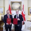 El secretario general To Lam y el primer ministro del Reino Unido, Keir Starmer, intercambian una declaración conjunta sobre la elevación de los nexos bilaterales a una asociación estratégica integral. (Foto: VNA)