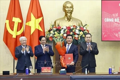 El primer ministro Pham Minh Chinh (segundo desde la izquierda) y el presidente de la Asamblea Nacional, Tran Thanh Man (extrema derecha), presentan la decisión del nombramiento y ofrecen flores a Nguyen Hong Dien. (Foto: VNA)