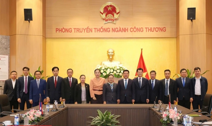 El ministro de Industria y Comercio, Nguyen Hong Dien (sexto desde la derecha), y la embajadora de Laos en Vietnam, Khamphao Ernthavanh (séptima desde la derecha), mantienen una sesión de trabajo. (Foto: tapchicongthuong.vn)