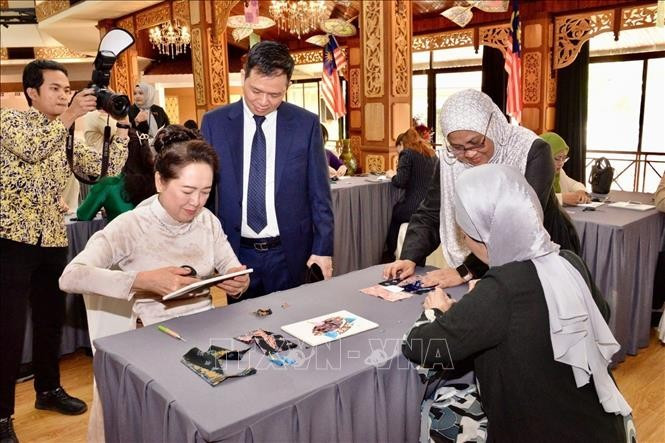 Nguyen Thi Thanh Nga, esposa del presidente del Parlamento de Vietnam y Rozana bintin Kamal, esposa del presidente de la Cámara de Representantes de Malasia, experimentan la impresión tradicional de telas. Foto: VNA