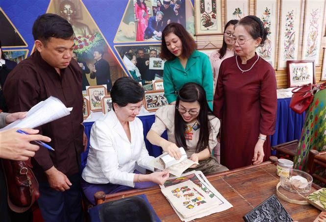 La esposa del primer ministro Pham Minh Chinh, Le Thi Bich Tran, y los delegados realizan pinturas folclóricas de Dong Ho (Foto: VNA)