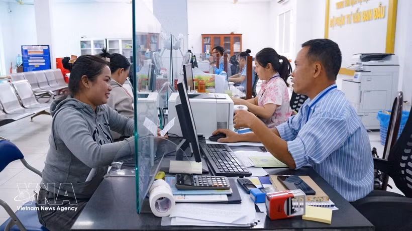 Funcionarios del Centro de Servicios Administrativos Públicos del barrio de Tan Ninh orientan a los residentes sobre los trámites administrativos en el entorno digital. (Foto: VNA)