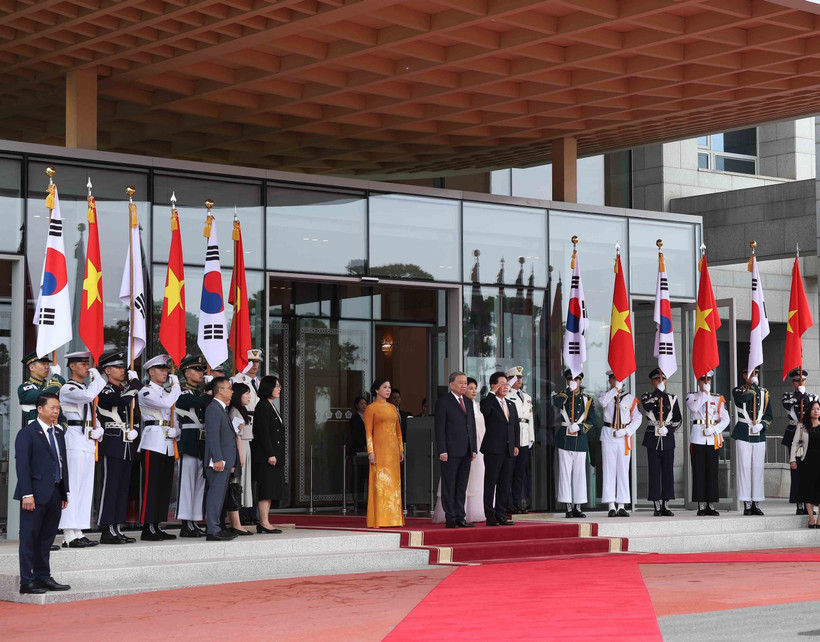 El presidente surcoreano, Lee Jae Myung, y su esposa, junto con el secretario general To Lam y su cónyuge, en posición de honor, escuchan a la banda militar interpretar los himnos nacionales de ambos países. Foto: VNA