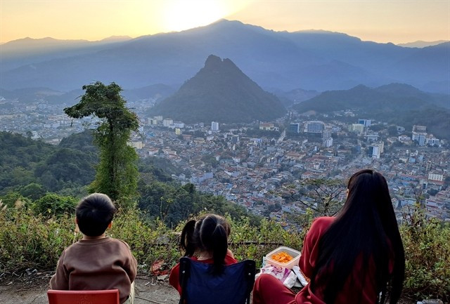 Turistas ven la puesta de sol sobre la ciudad de Hà Giang desde la montaña Mỏ Neo.— Foto: VNA