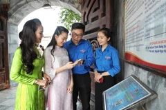 Jóvenes guían a los turistas para que escaneen códigos QR y aprendan sobre el sitio histórico de la Victoria de Xuong Giang. (Foto: VNA)