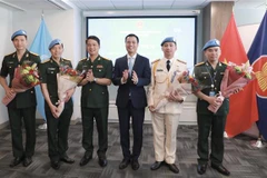 El embajador Dang Hoang Giang, jefe de la misión permanente de Vietnam ante la ONU, entre flores a oficiales connacionales participantes en las actividades del mantenimiento de la paz de las Naciones Unidas. (Fuente:VNA)