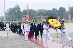 Los delegados depositan una ofrenda de flores en homenaje al Presidente Ho Chi Minh en su mausoleo. (Foto: VNA)