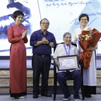 La directora general de VNA, Vu Viet Trang (primera, a la izquierda), entrega el Premio "Caballero Grillo" al compositor Pham Tuyen (sentado) durante la ceremonia. (Foto: VNA)