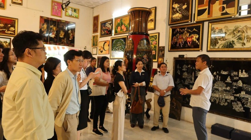 Visitantes escuchan la presentación sobre la historia de la laca en el taller de producción de Dinh Hoa. (Foto: Vietnam+) 