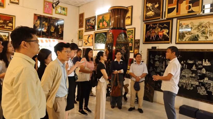 Visitantes escuchan la presentación sobre la historia de la laca en el taller de producción de Dinh Hoa. (Foto: Vietnam+) 