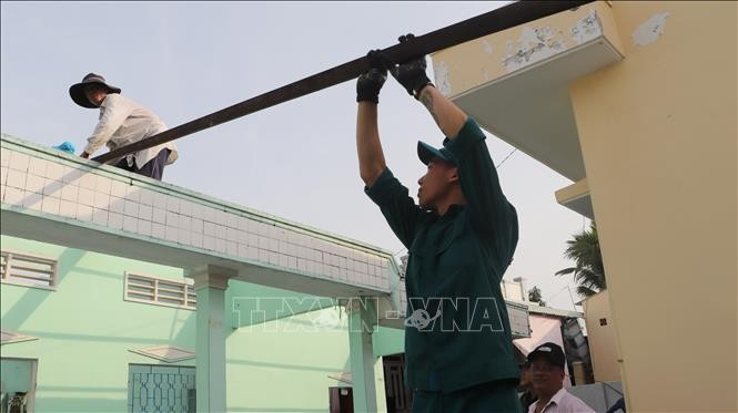 La fuerza armada del pueblo de Long My, provincia de Hau Giang, ayuda a los pobladores a eliminar viviendas temporales y precarias. (Fuente: VNA)