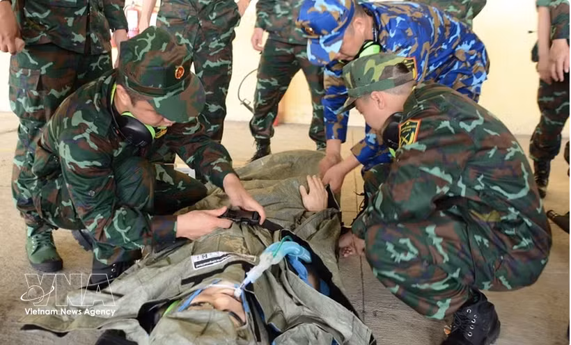 Los miembros del equipo AMET practican la recepción y sujeción de un paciente en una camilla para su traslado a una ambulancia (Foto: VNA)