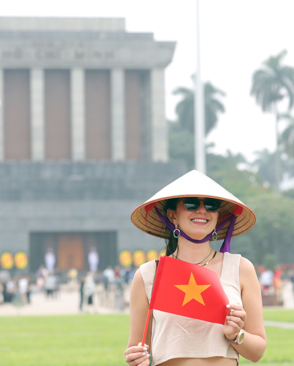 Los visitantes extranjeros disfrutan tomándose fotos con la bandera vietnamita. (Foto: VNA)