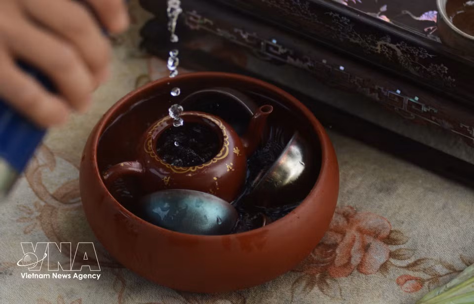 Antes de preparar el té de loto, el artesano limpia y calienta la taza. Foto: VNA