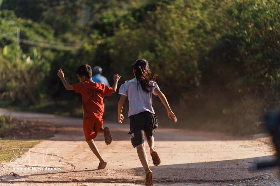 Niños jugando en el camino del pueblo, transmitiendo una sensación de paz y autenticidad. Foto: VNA