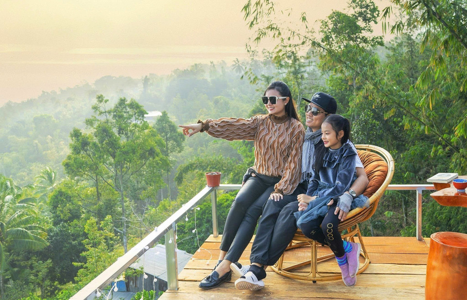Una familia de turistas disfruta del té, saludando el amanecer en la cima de la montaña Cam. (Foto: VNA)