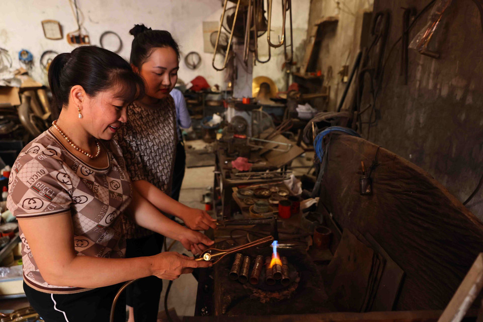 La esposa y la hija de Nguyen Van Huong en el proceso de soldadura de trompetas. (Foto: VNA)