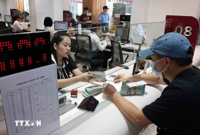 Clientes realizan transacciones en la sucursal del banco Agribank Hanoi. (Foto: Tran Viet/VNA) lam-phat-1.jpg