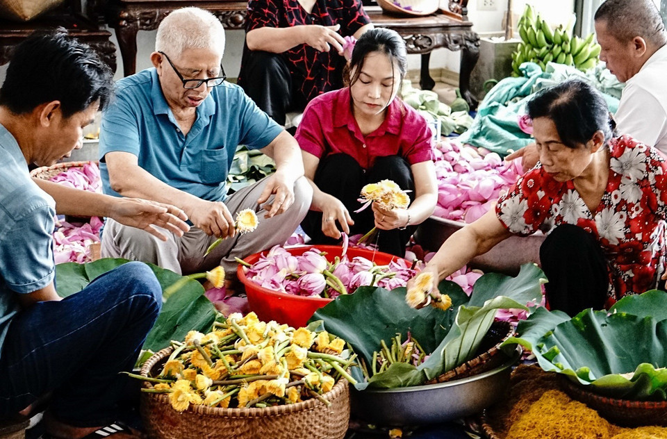El artesano Ngo Van Xiem, de 78 años de edad, y los miembros de su familia maceran el té con loto. (Fuente: VNA)