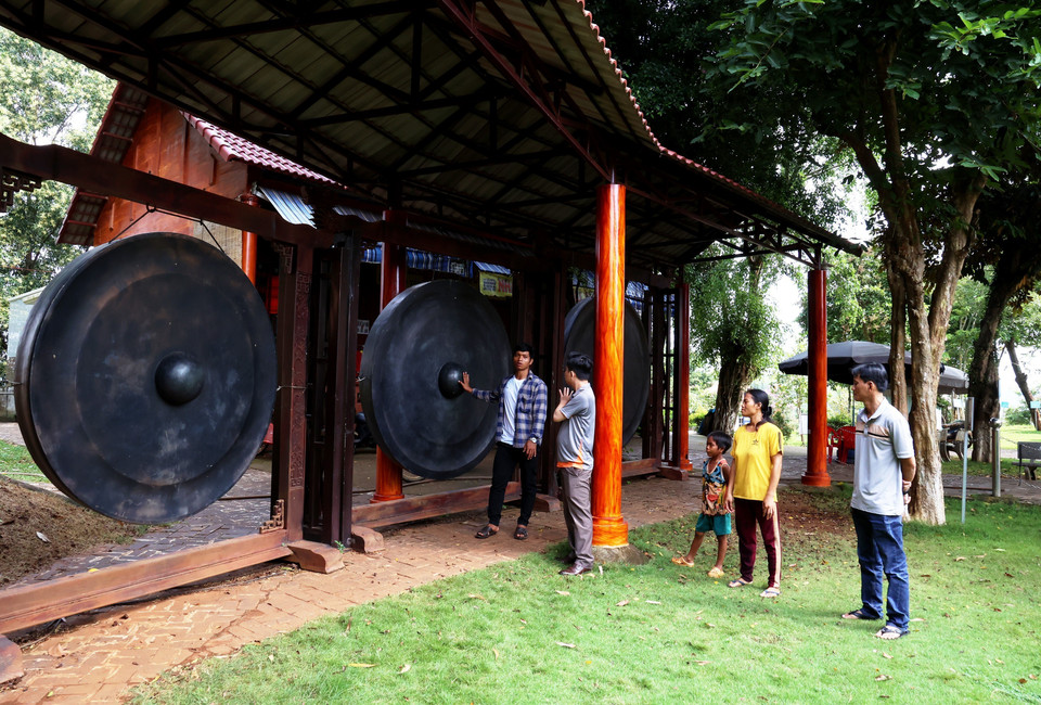 Los turistas aprenden sobre el conjunto de gongs más grande de Vietnam exhibido en el Área. (Foto: VNA)