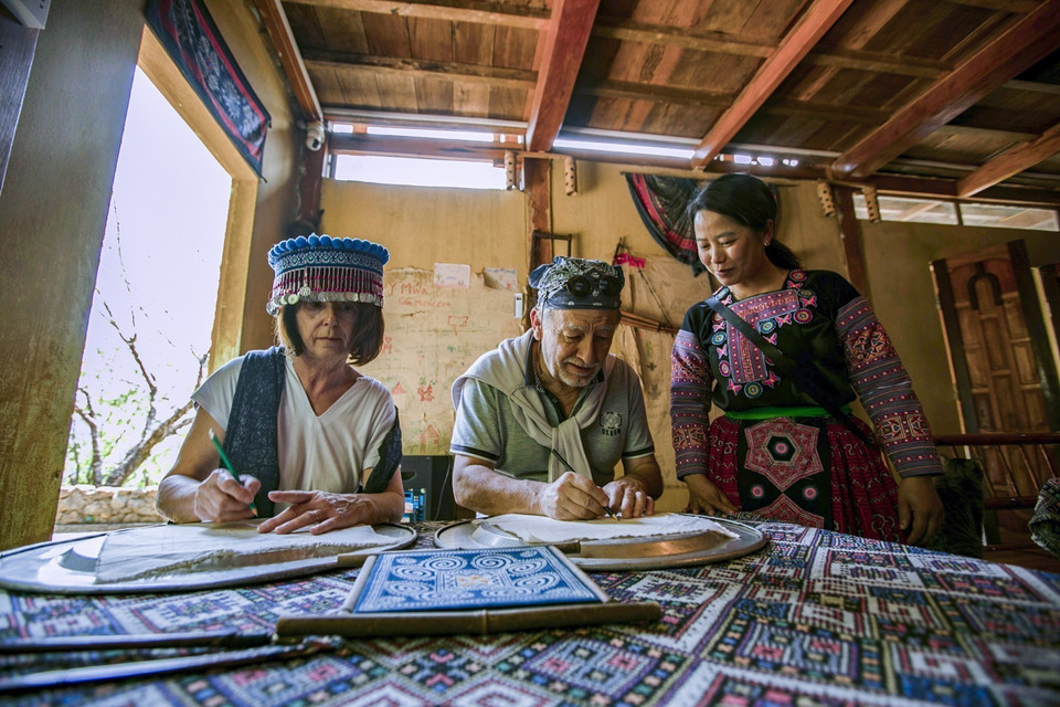 Los turistas franceses pintan sobre el brocado típico de la etnia Mong en el homestay Y Mua, comuna de Hang Kia. (Foto: VNA)