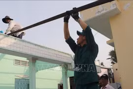 La fuerza armada del pueblo de Long My, provincia de Hau Giang, ayuda a los pobladores a eliminar viviendas temporales y precarias. (Fuente: VNA)