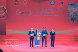 El miembro del Buró Político y jefe de la Comisión de Propaganda, Educación y Movilización de Masas del Comité Central del Partido Comunista de Vietnam, Trinh Van Quyet, entrega el premio A a los galardonados. (Fuente: VNA)