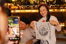 Una turista disfrutan del turismo nocturno en el Templo de Literatura, Hanoi (Fuente: VNA)