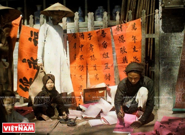 Un calígrafo escribe frases paralelas para la decoración del Tet en una calle de Hanoi, hace más de un siglo (Fuente: VNA)