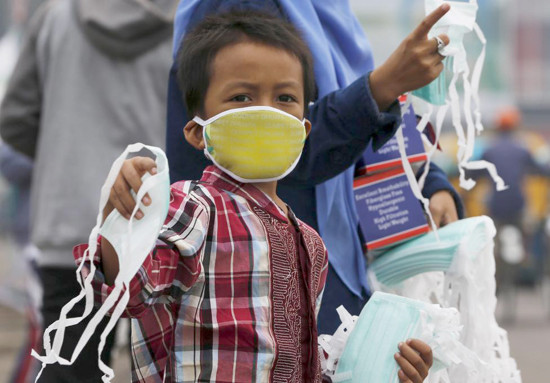 La polución hace las mascarillas un artículo bien vendido. En la foto, un niño vende mascarilla en la isla Sumatra. 