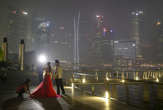 Una pareja saca fotos de boda en un distrito céntrico de Singapur. El humo rodea a ellos.