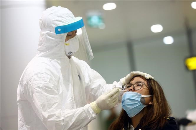 Un trabajador de salud toma muestras de una pasajera después de que se complete la declaración médica y se mida la temperatura corporal (Foto: VNA)