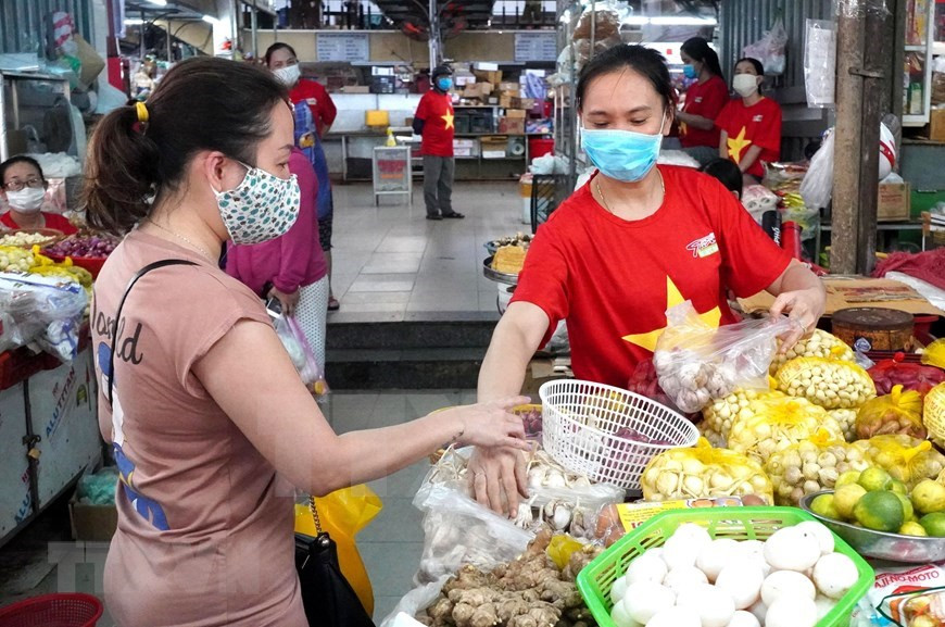 Vendedores del mercado Dong Da usan camisetas de la bandera nacional para mostrar determinación de combatir contra la pandemia (Foto: VNA)