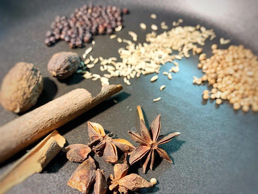 Mientras tanto vamos a preparar el resto de ingredientes: cortar la cebolla en juliana fina, separar la parte blanca de la cebolleta y picar la parte verde junto al cilantro, cortar en juliana la parte blanca de la cebolleta y cortar la ternera finamente. Cocinar al grill la cebolla, chalota, jengibre, canela y anís estrellado. Con la ayuda de un cuchillo quitar las partes más quemadas dejando un poquito. Reservar para luego. Tostar las especias. Ponerlas en una bolsita de infusión y reservar para luego. Para preparar el bol: coger una ración de tallarines de arroz y escaldar en agua hirviendo durante 15 segundos. Luego ponerlos en el bol. Colocar las carnes encima. (Fuente: VietnamPlus)