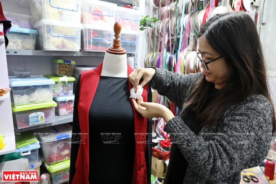 Ngo Thi Thom engancha los broches a los trajes de sus clientes (Foto: VNA)