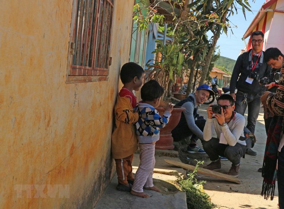 Un grupo de turistas toman fotos de niños locales (Fuente: VNA) 
