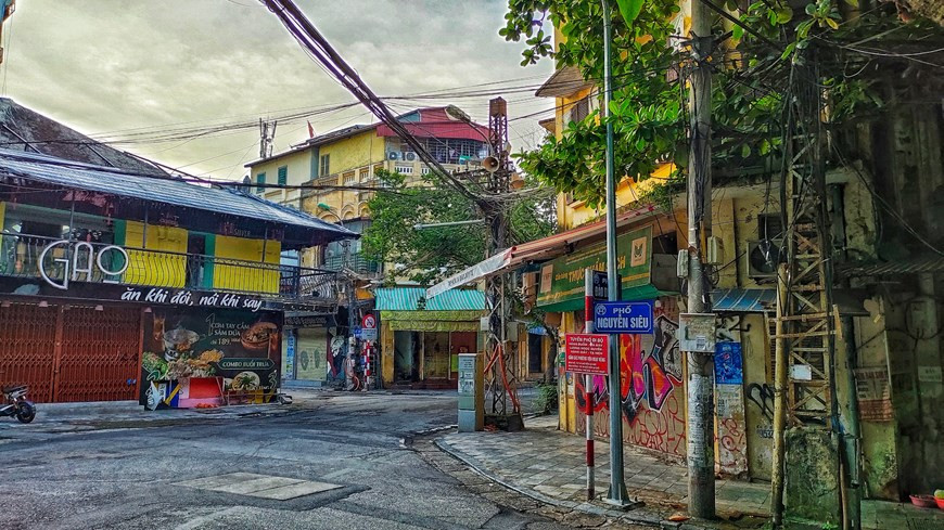 Una calle vacía en Hanoi durante el distanciamiento social. Según las regulaciones, las agencias, empresas y corporaciones (incluidas aquellas con inversión extranjera) deben cumplir las normativas para garantizar que su personal trabaje en línea y solo vaya a las oficinas en caso de necesidad. Los centros comerciales, tiendas, mercados tradicionales y mayoristas de la ciudad deben garantizar el suministro adecuado de los productos esenciales a la población local, organizar los puestos y los procedimientos de recepción (desde el estacionamiento hasta la entrada) para reducir el número de clientes en un solo lugar al mismo tiempo, a la par de minimizar los contactos cercanos e incentivar las compras y entregas en línea. (Foto: Vietnam+)