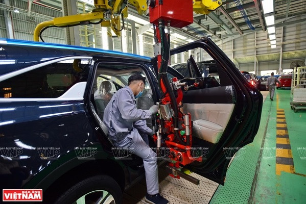 Trabajadores usan brazos robóticos para ensamblar puertas de automóviles. (Foto: VNA)