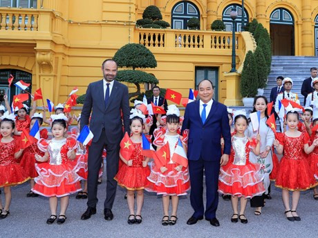 Los dos premieres toman una foto con los niños vietnamitas (Fuente: VNA)