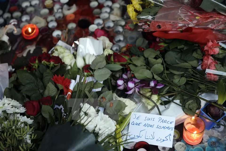 Candelas y flores colocadas en la entrada del café La Belle Equipe en París (Fuente: AFP/TTXVN)