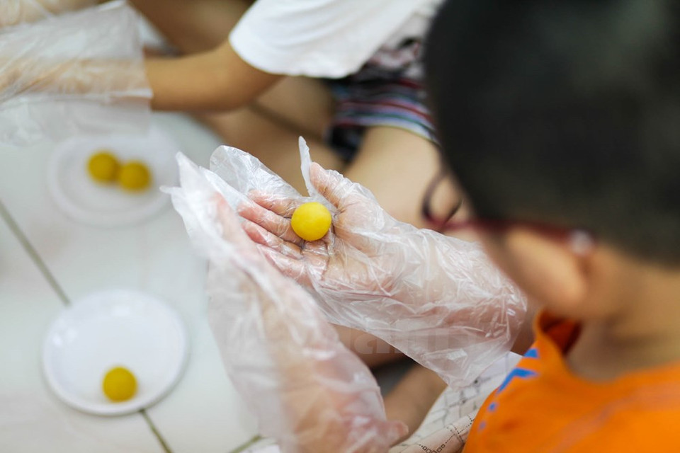 Un niño forma la guarnición – hecha de frijol verde cocido a vapor – en bola. (Fuente: VNA)