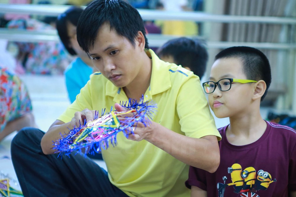 Un padre reajusta el producto de su hijo. (Fuente: VNA)