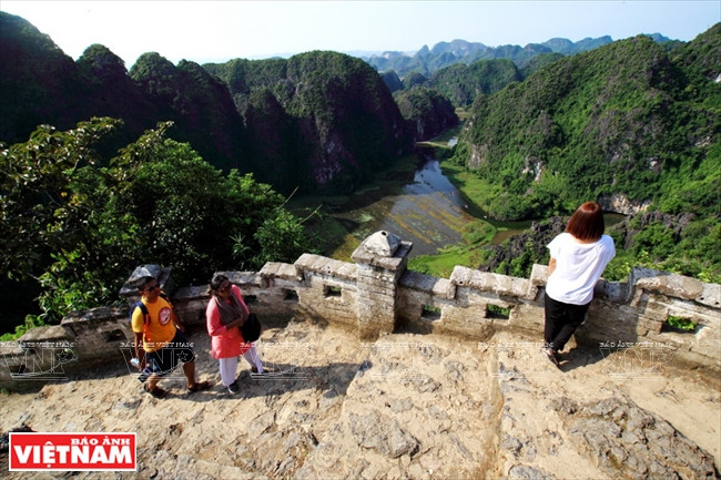 Al subir los escalones hacia la cima, los turistas disfrutan de una maravillosa vista del panorama de la hermosa tierra de Ninh Binh.