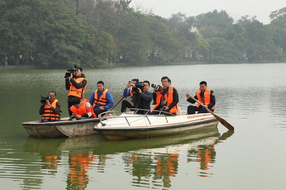 El fotoperiodista Tri Dung de VNA y un reportero de televisión vietnamita en un barco en medio del lago Hoan Kiem para cubrir el evento “Primavera en la tierra natal” en 2019. (Foto: VNA)