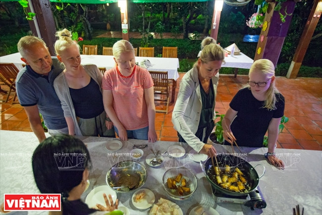 Los extranjeros aprenden a hacer rollitos de primavera vietnamitas fritos como parte de un recorrido por el huerto Ben Tre. Foto: Dang Kim Phuong